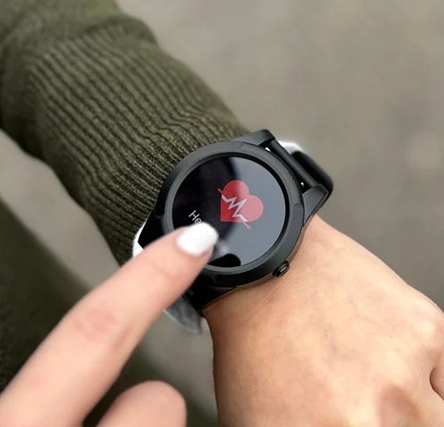 The medical alert smartwatch worn on a wrist, showing its heart-rate screen.